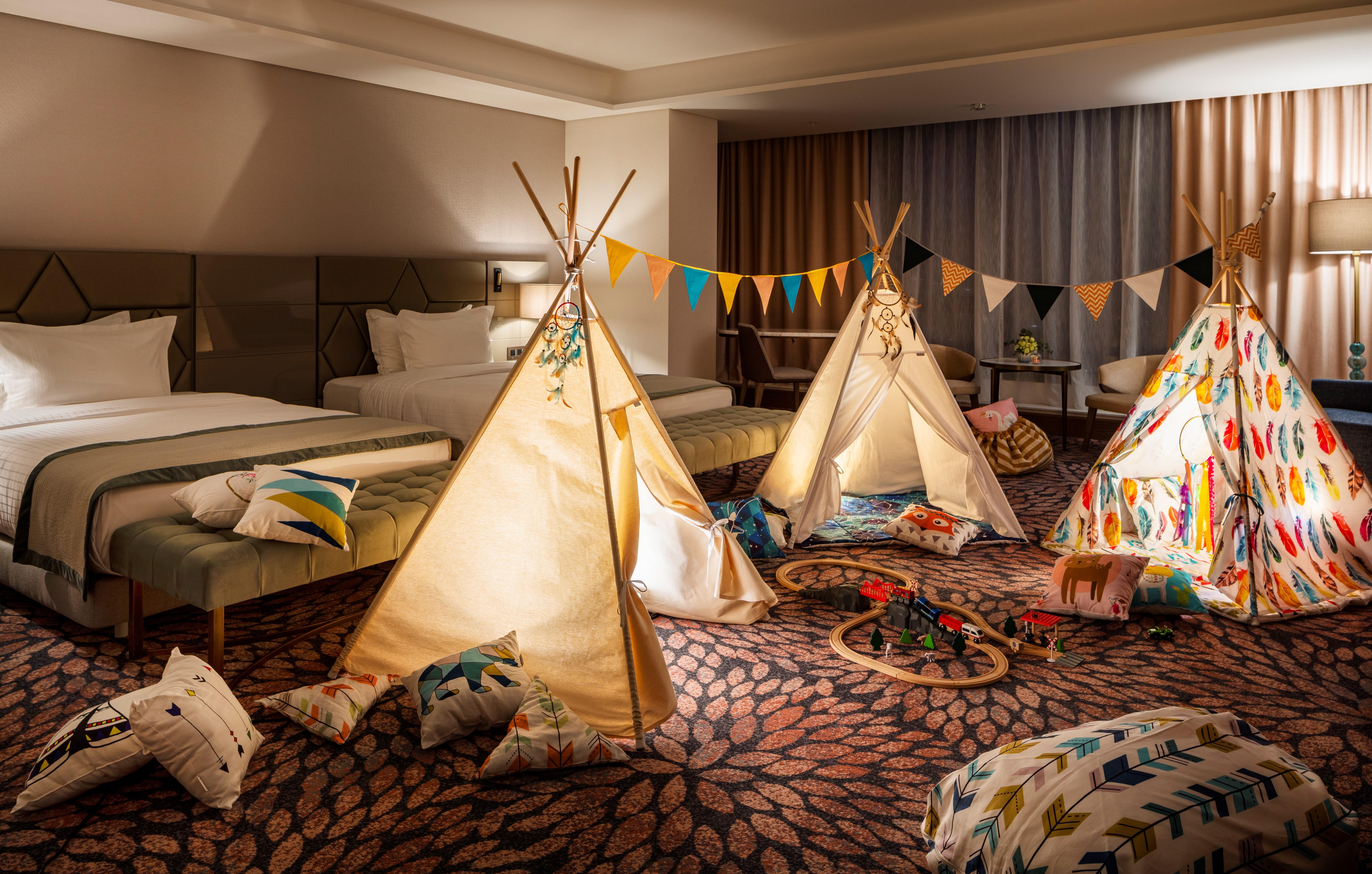 Grand Hotel Millennium Sofia Ngoại thất bức ảnh The photo shows a cozy room featuring three children's teepees made of fabric, arranged in a playful manner. The teepees are decorated with colorful patterns and surrounded by various cushions and pillows scattered on the floor. There are also decora