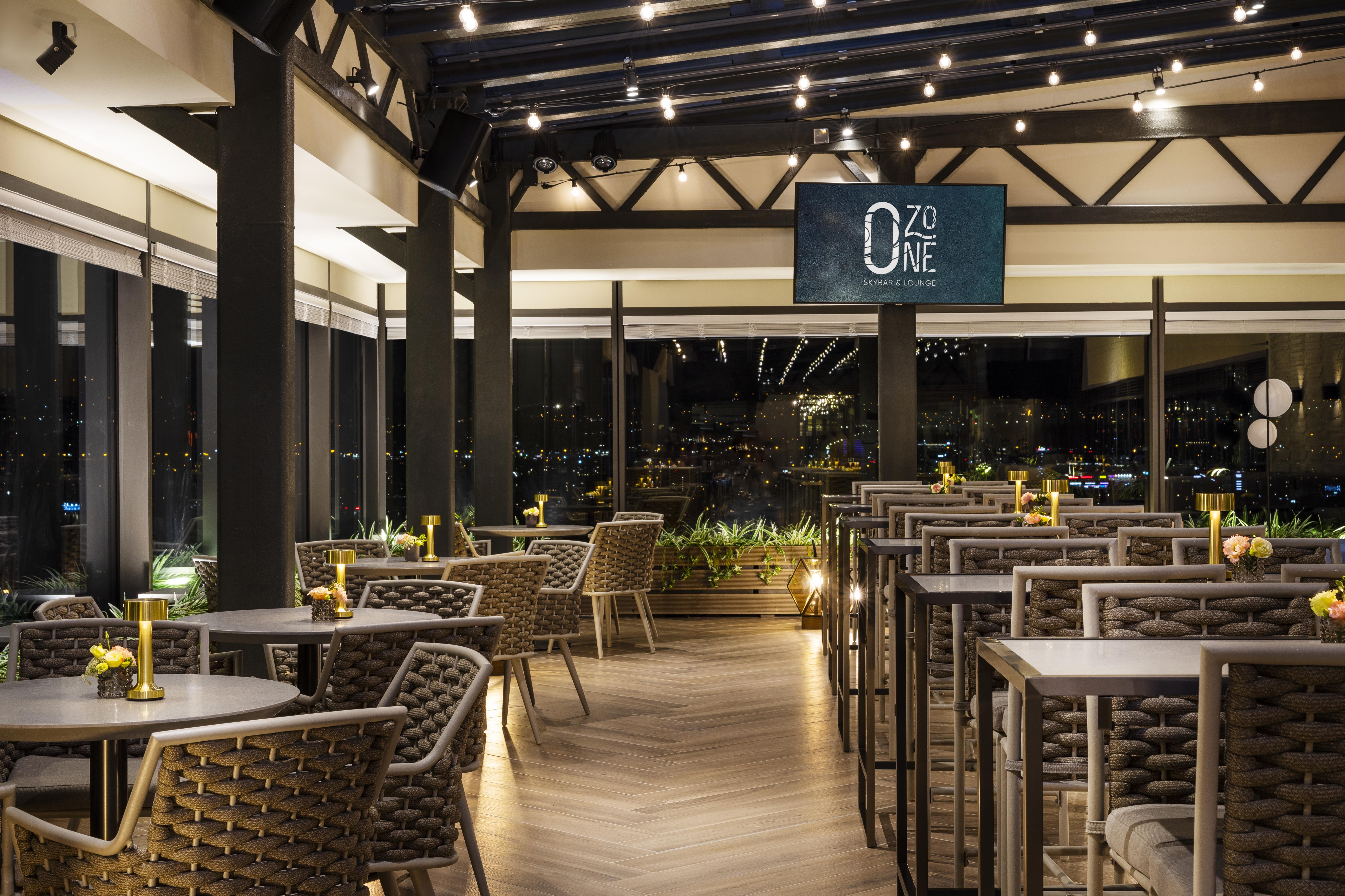 Grand Hotel Millennium Sofia Ngoại thất bức ảnh The photo depicts a modern restaurant interior with a stylish design. The space features a series of tables and chairs arranged neatly, with a clean and sophisticated aesthetic. The tables are set with small yellow flowers, adding a touch of color to
